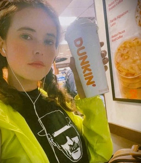 Miriam wearing a yellow coat, at Dunkin Donuts.